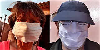 Zwei Personen nebeneinander, eine mit rotem Oberteil und die andere mit blauer Kappe, beide mit Mund-Nasen-Schutz