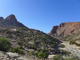 Berglandschaft im Antiatlas mit einer Landstraße, einem Dorf und terrassierten Hängen unter klarem Himmel