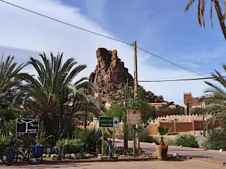 Felsformation in Tafraout mit Palmen, Straßenschildern und Gebäuden im Vordergrund unter blauem Himmel