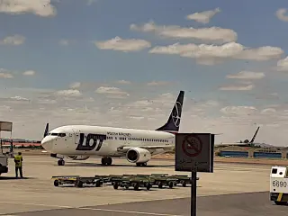 Flugzeug der LOT Polish Airlines auf dem Rollfeld mit mehreren Personen und einem Schild mit Rauchverbot