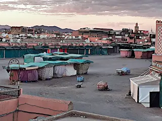 Leerer Marktplatz Djemaa el Fna in Marrakesch mit geschlossenen Ständen und Gebäuden im Hintergrund