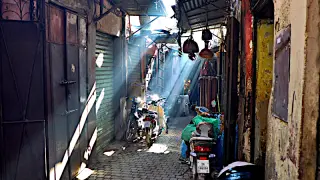 Enger, schattiger Gasse in der Altstadt von Marrakesch mit Lichtstrahlen, Motorrädern und hängenden Körben