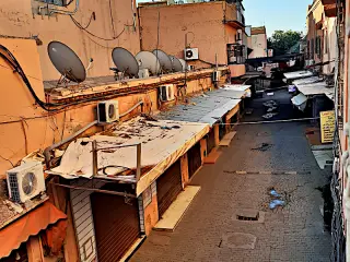 Leere Straße in Marrakesch mit geschlossenen Läden, mehreren Satellitenschüsseln und Klimaanlagen an den Gebäudefassaden