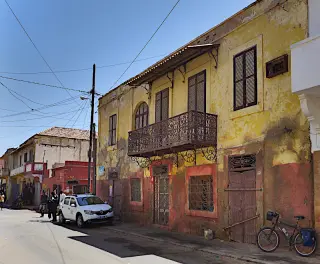 Straße in St. Louis mit zweistöckigem Gebäude mit Balkon und mehreren Fenstern sowie weißen Auto und Fahrrad am Straßenrand