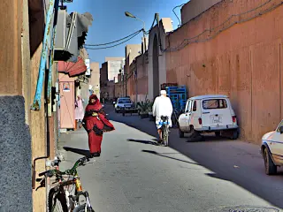 Eine Frau in traditioneller roter Kleidung auf der Straße , während ein Mann auf seinem Fahrrad an ihr vorbeifährt